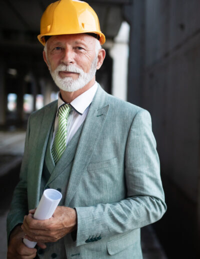 Smiling construction manager, engineer, businessman, architect standing on construction site